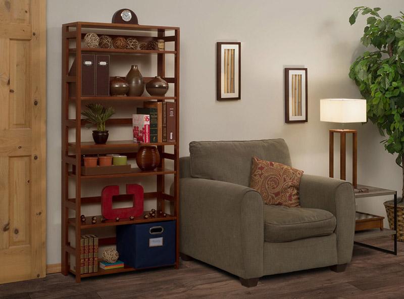 67 inch flip flop folding medium oak bookcase in a living room with a chair and side table with a lamp and photos on the wall