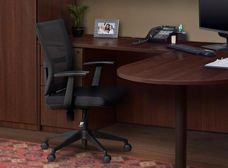 mahogany L desk with a rounded return next a black swivel chair